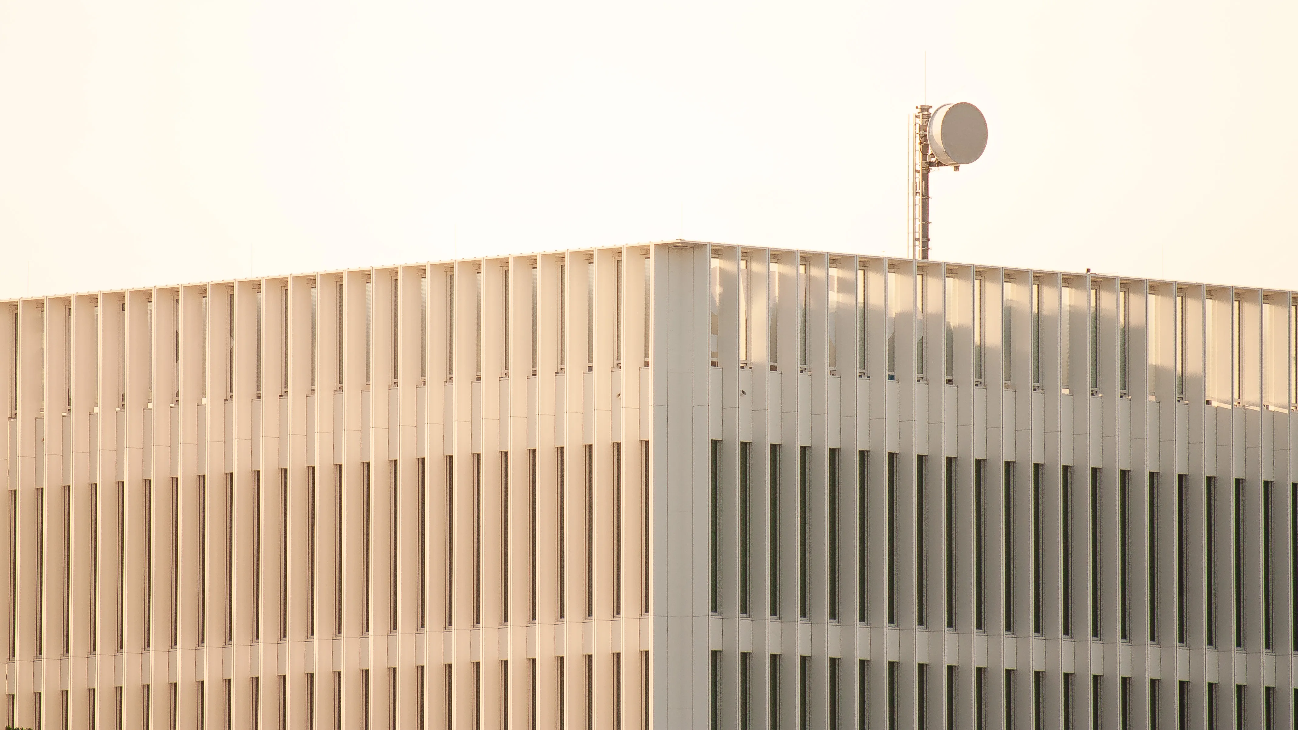 A single microwave antena sits atop a modern building.