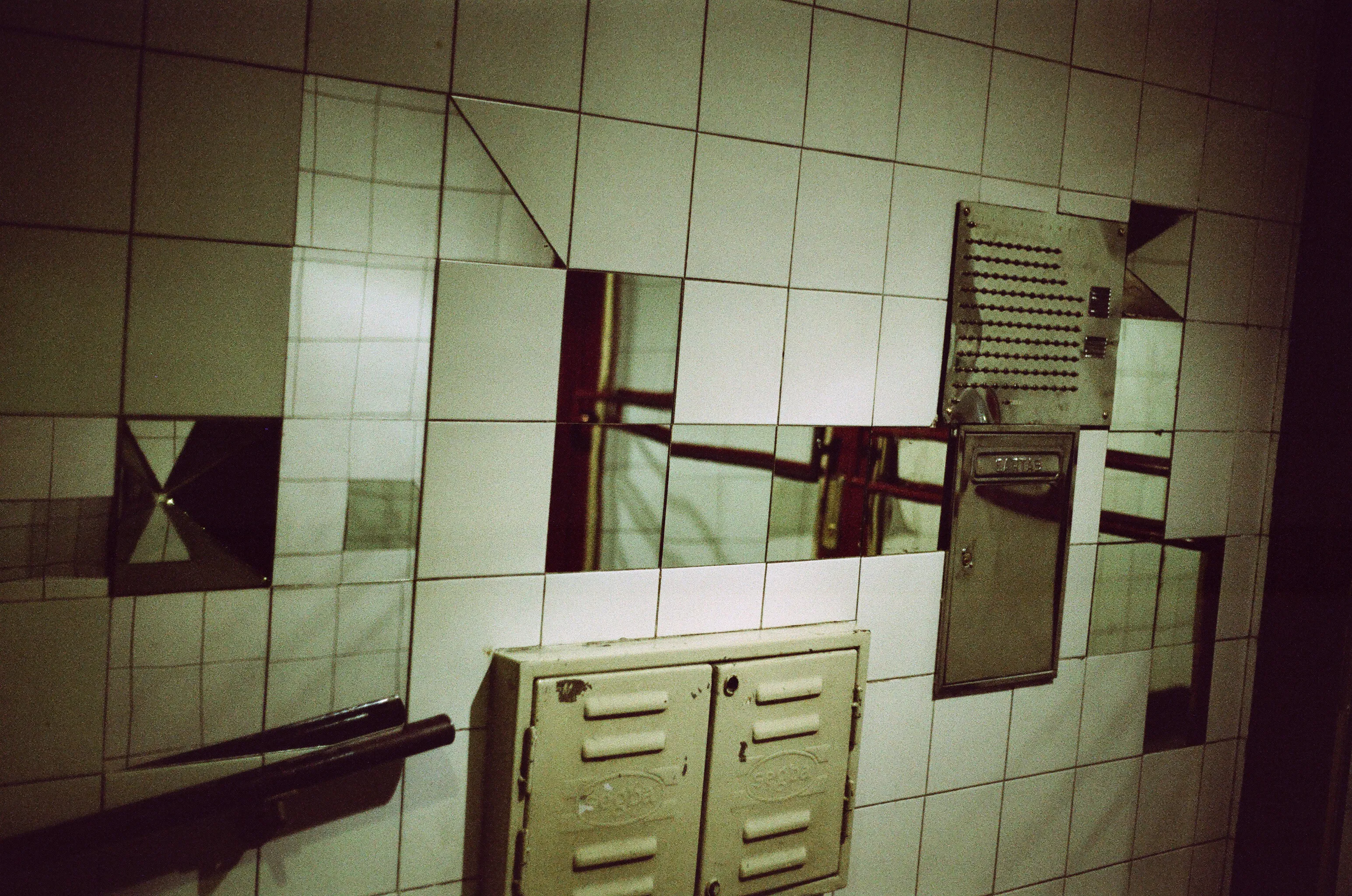 A hallway leading into a building, covered in tiles, with some tiles replaced by mirrors.