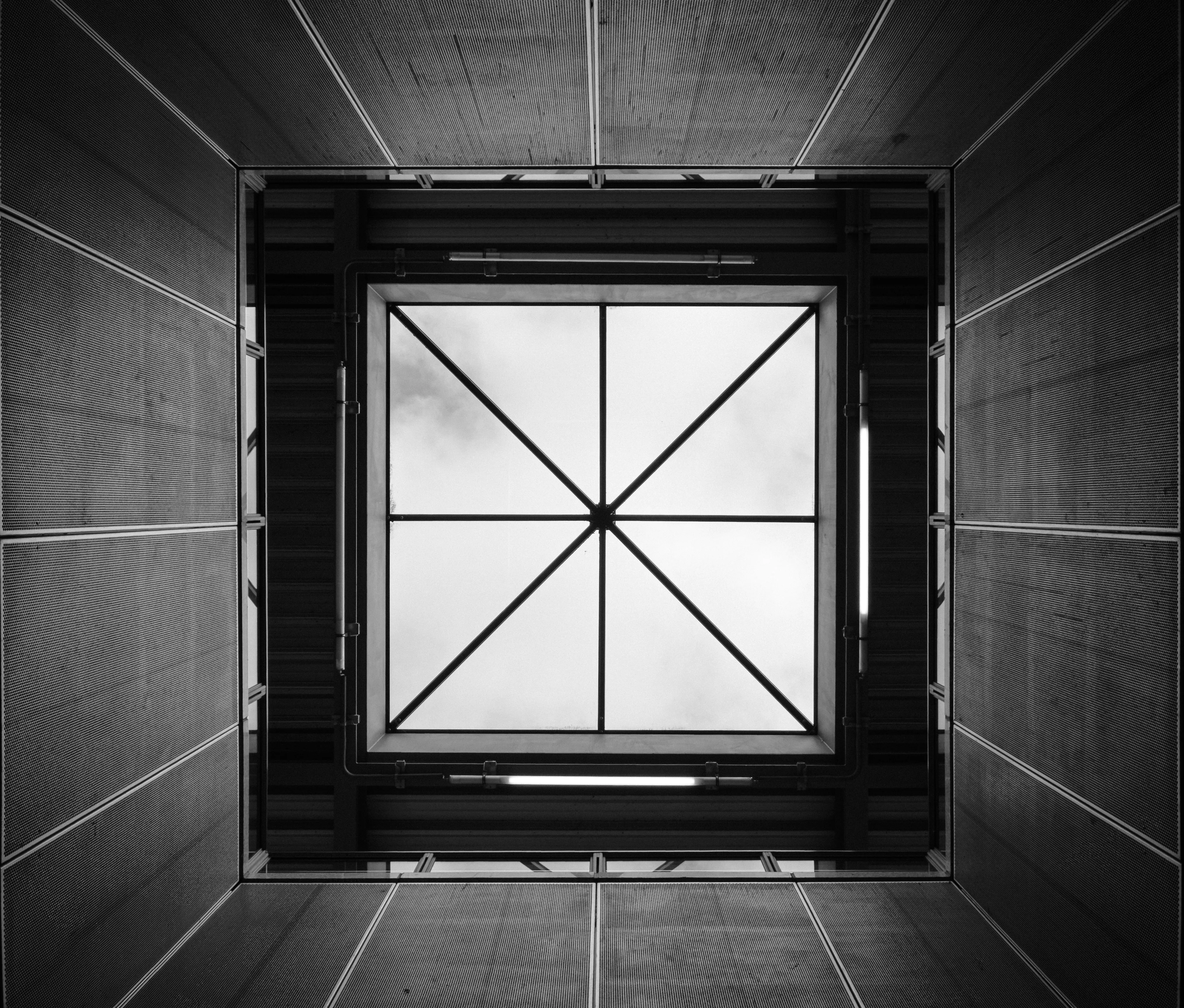 The roof of a train station. A pyramid-shaped skyglass shows the clouds above.